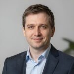 Профессиональный портрет уверенного российского бизнесмена с дружелюбным взглядом на размытом нейтральном фоне